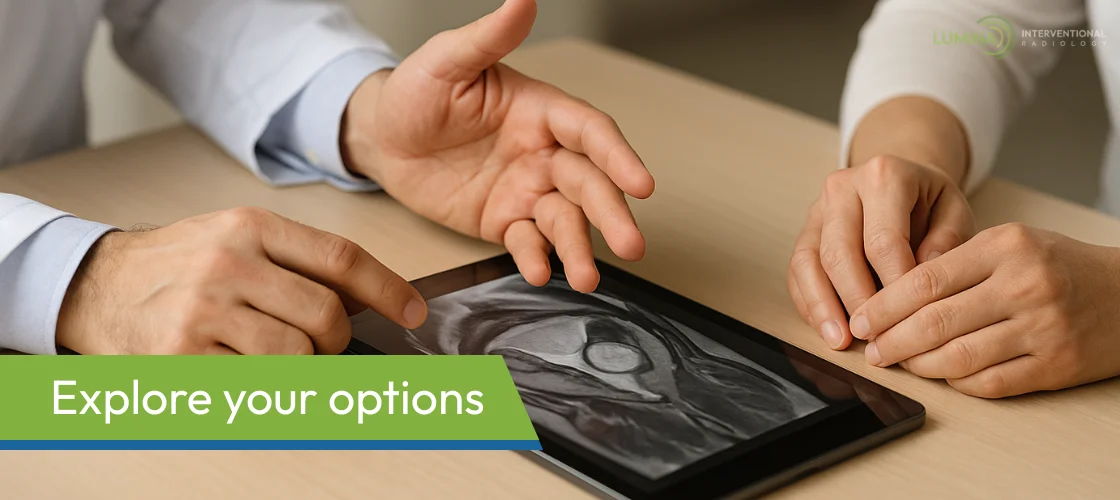 Doctor and patient discussing fibroid ultrasound on tablet screen.